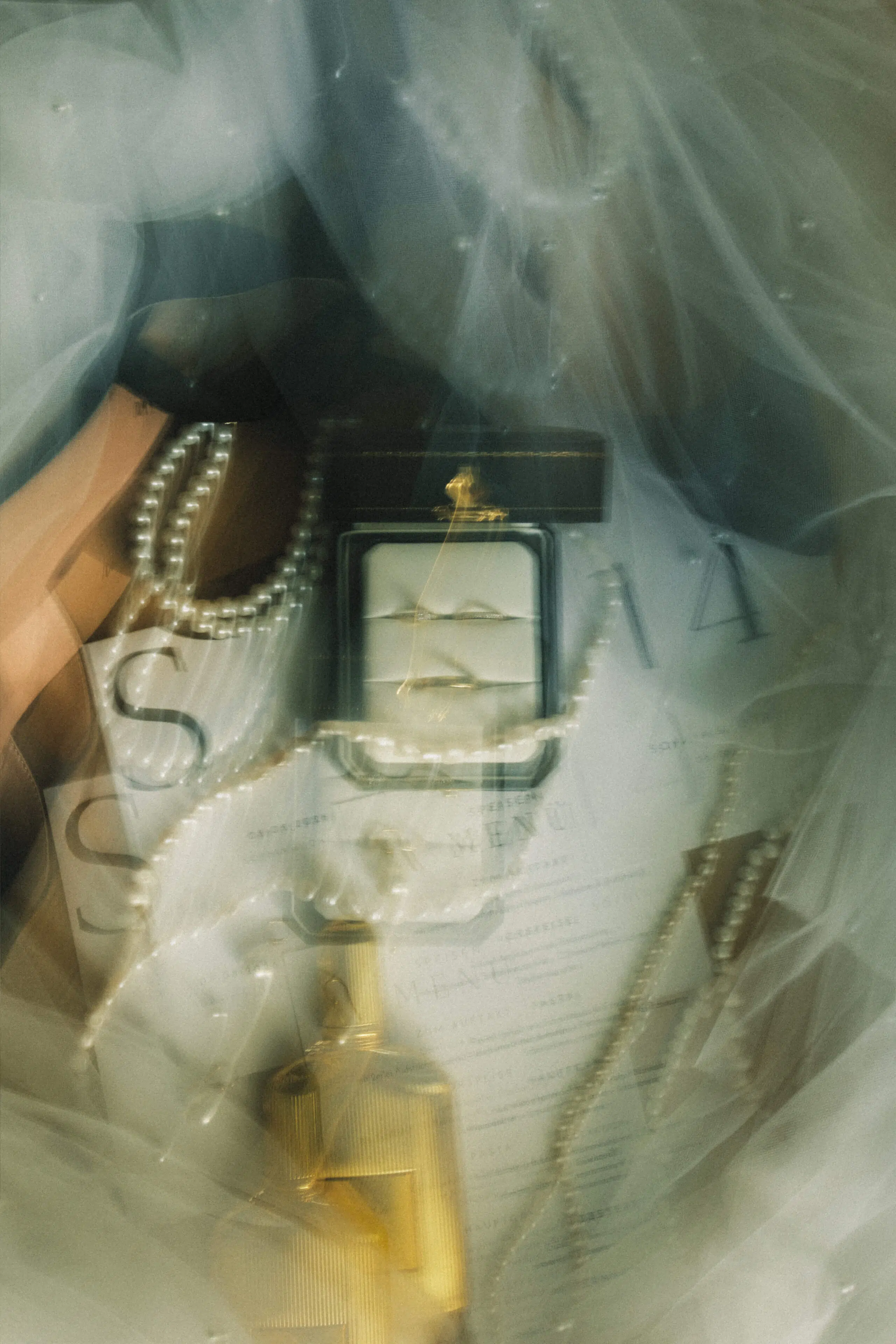 Eheringe, Perlenkette, Menükarte und Parfum unter einem Schleier